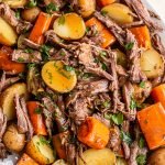 close up photo of venison roast, potatoes, and diced carrots topped with parsley