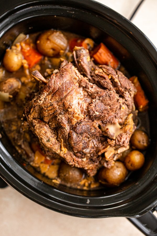 Venison roast in crock pot over small yellow potatoes, dices carrots and seasonings