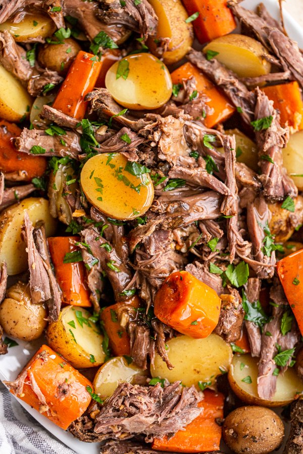  photo en gros plan de rôti de chevreuil, de pommes de terre et de carottes coupées en dés garnies de persil 