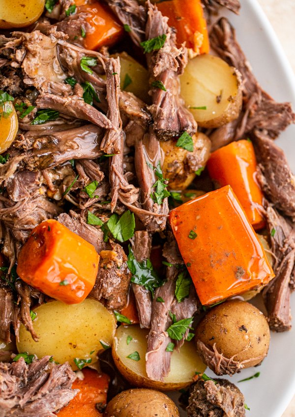 close up photo of venison roast, potatoes, and diced carrots topped with parsley