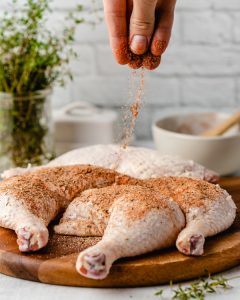 Raw chicken legs begin seasoned with a mixture of spices
