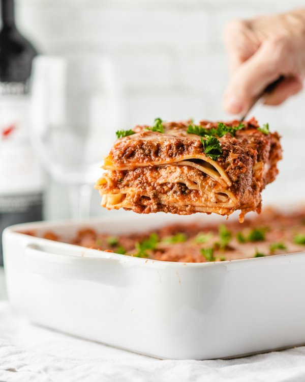 taking a slice of venison lasagna out of a pan