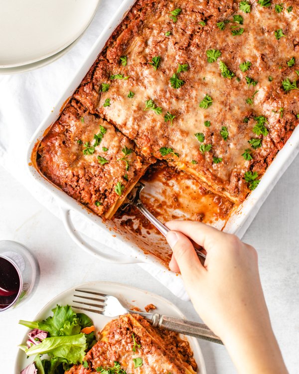 taking a slice of venison lasagna out of a pan