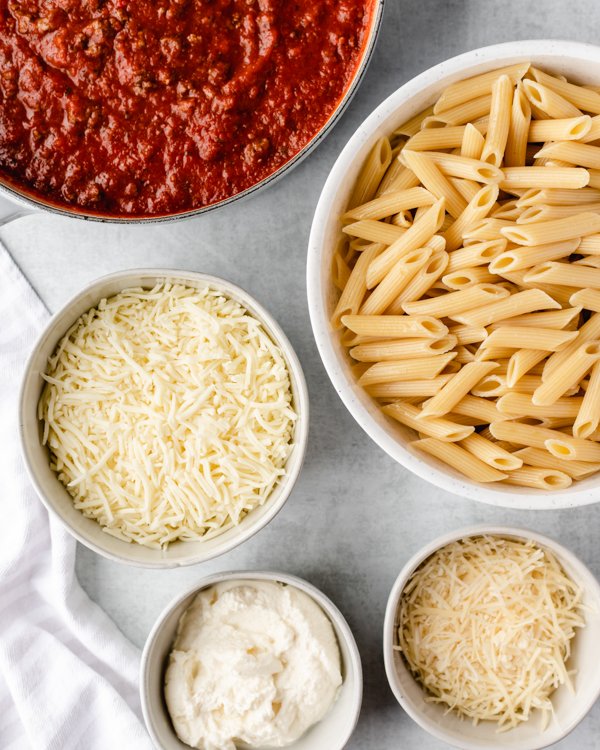 penne, sauce and cheese on a counter