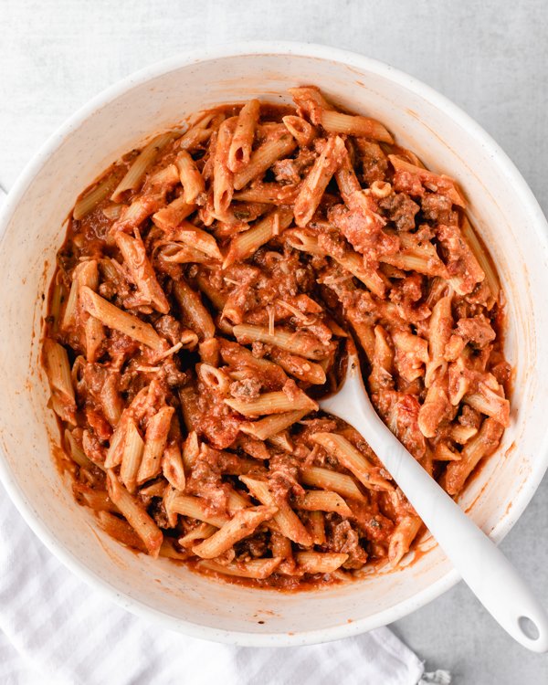 pasta and sauce mixed together in a white bowl