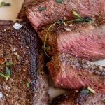 venison chops on a white plate with salt and thyme