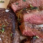 venison chops on a white plate with salt and thyme