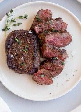 venison chops on a white plate with salt and thyme