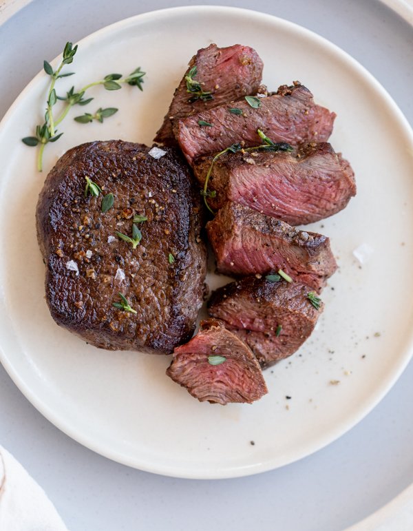 venison chops on a white plate with salt and thyme