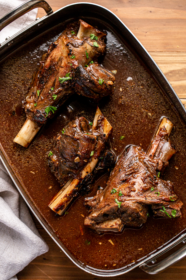 venison shank in a roasting dish with braising liquid