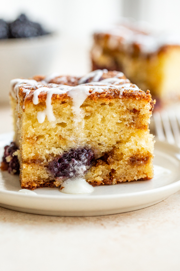 blackberry coffee cake with a glaze on a white plate