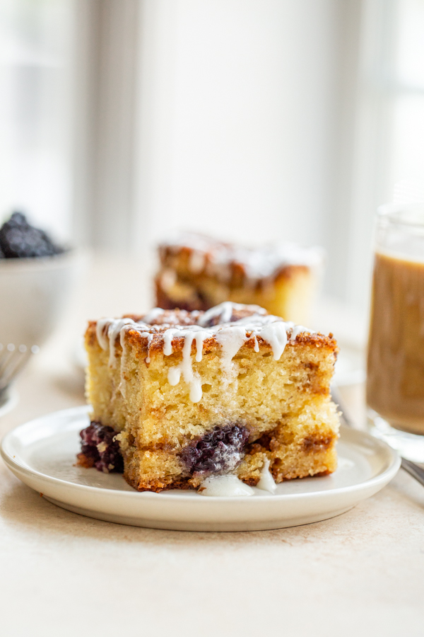 blackberry coffee cake with a glaze on a white plate