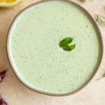 creamy garlic and herb sauce in a bowl with a basil leaf