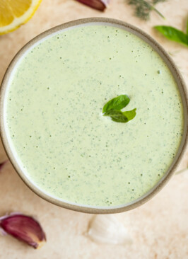 creamy garlic and herb sauce in a bowl with a basil leaf