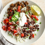 venison burrito bowls with sour cream, cheese and black beans in a white bowl