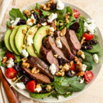 venison steak salad in a bowl with goat cheese, tomatoes, avocado and walnuts