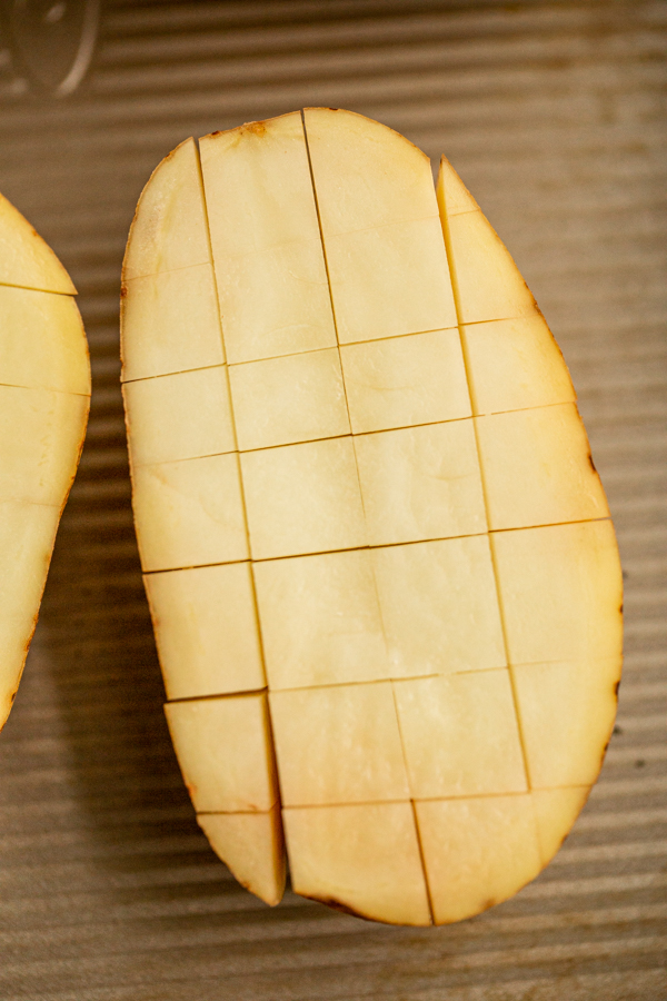 a potato on a baking sheet with cuts in it