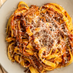 venison ragù on a grey plate with pasta and grated cheese