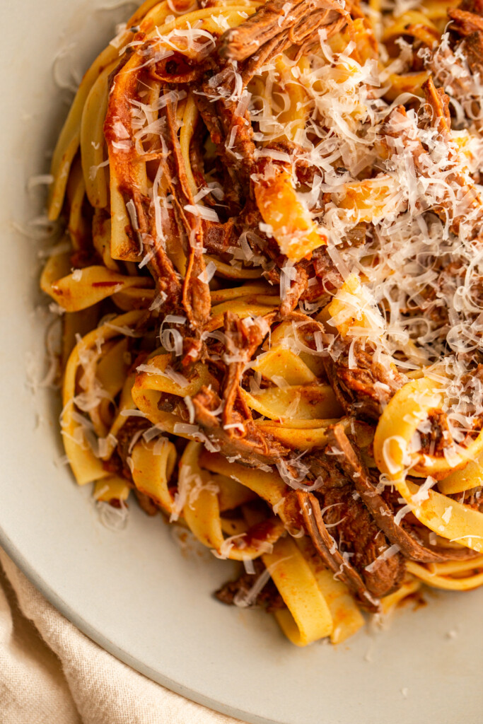 venison ragù on a grey plate with pasta and grated cheese