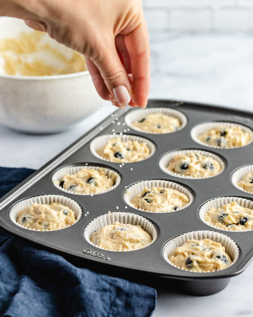 sprinkling sugar on blueberry muffins