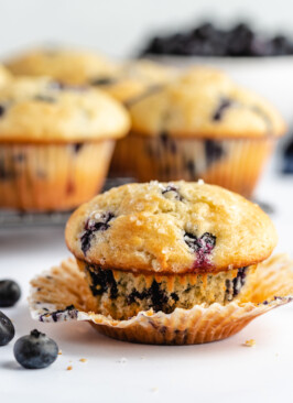 Greek yogurt blueberry muffins on a white counter with fresh blueberries