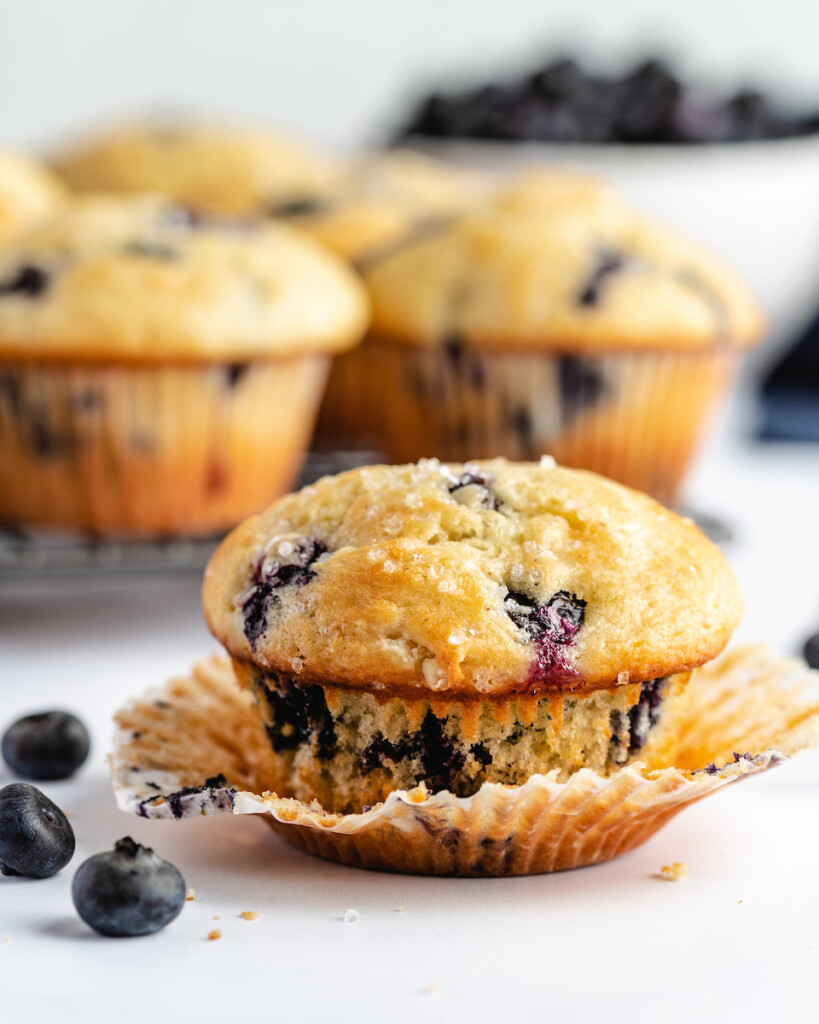 Greek yogurt blueberry muffins on a white counter with fresh blueberries