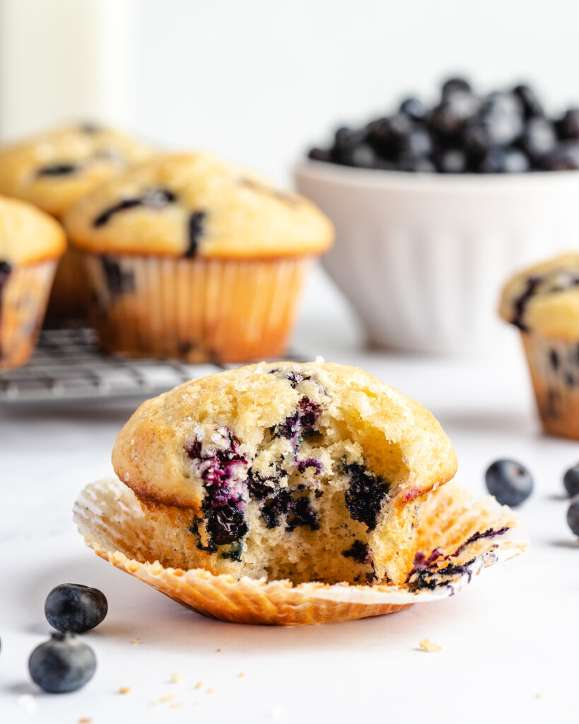 Greek yogurt blueberry muffins on a white counter with fresh blueberries