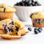 Greek yogurt blueberry muffins on a white counter with fresh blueberries