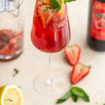 a wine glass with a red drink including wine, strawberries and seltzer