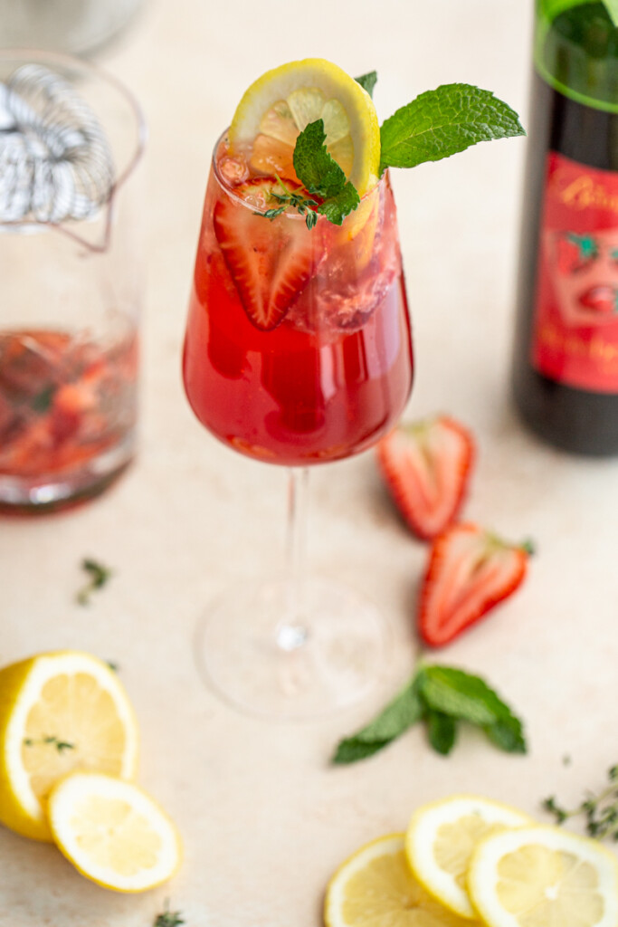 a wine glass with a red drink including wine, strawberries and seltzer