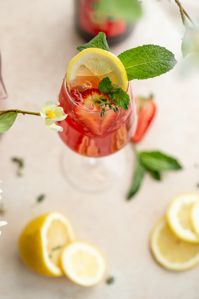 strawberry wine spritzer with lemon, strawberries and mint in a wine glass
