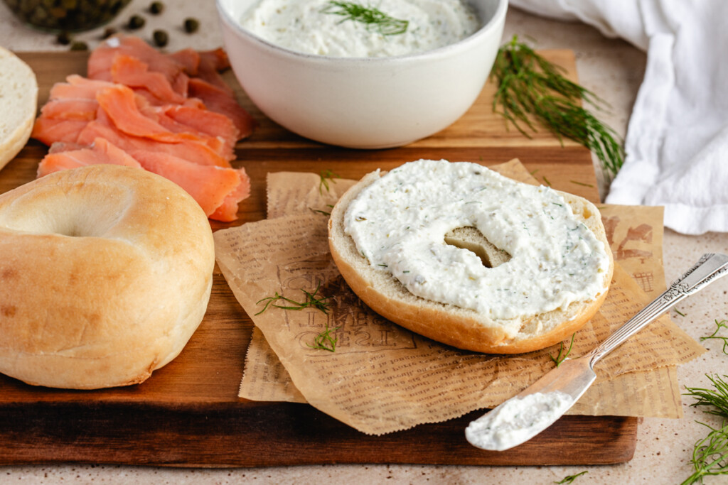 Bagel on cutting board with lox and fresh dill