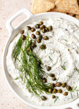 Cottage Cheese Caper Dill Dip in white round dish with crackers beside it