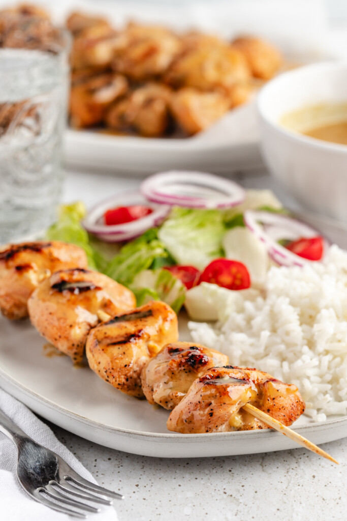 Grilled honey mustard chicken kebab on plate with white rice and salad