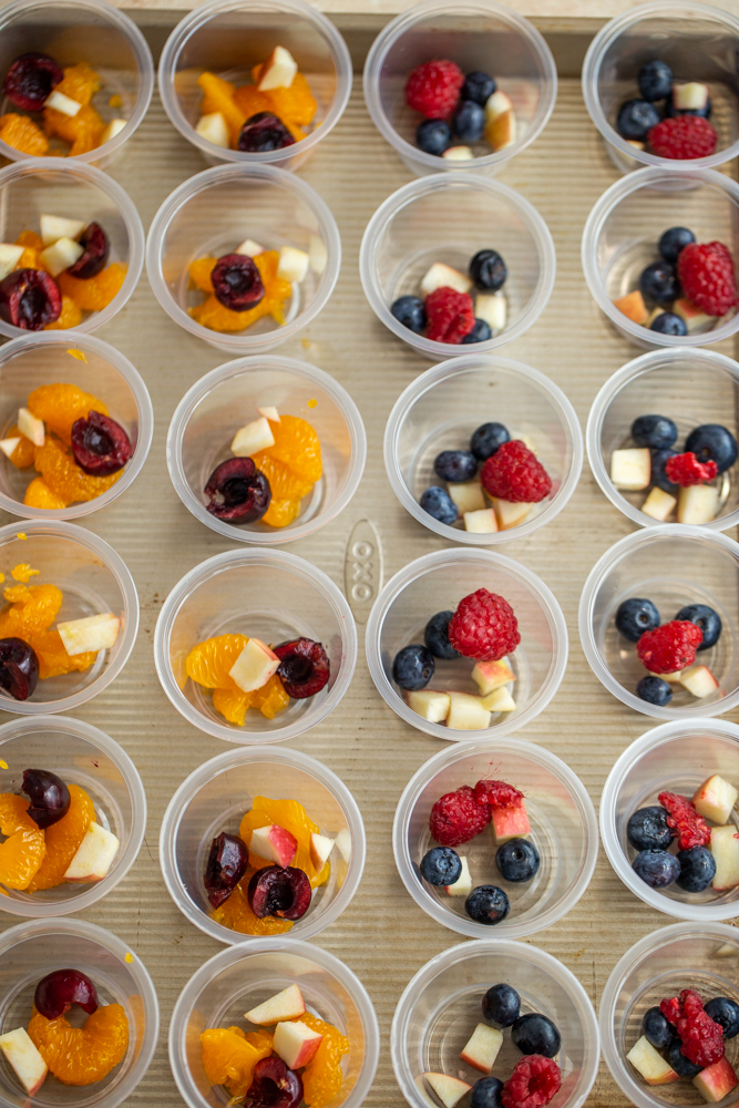 mini plastic cups filled with oranges, berries and apples