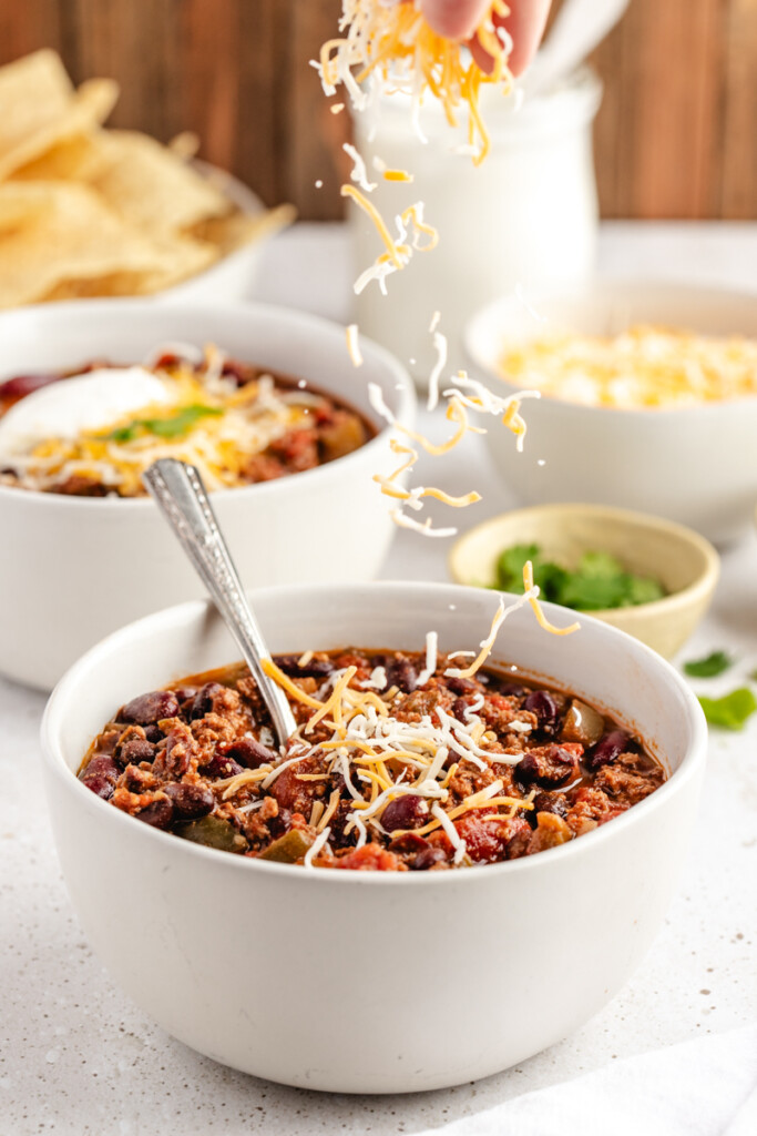 Shredded cheese being sprinkled on Slow Cooker Venison Chili