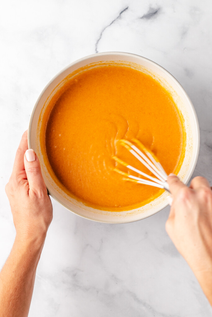 Mixing pumpkin bread in white bowl with whisk