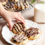 Childs hand taking a Baked Shortbread Cookie with Orange & Cranberry off a white plate