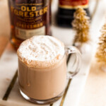 spiked hot chocolate in a glass mug with whipped cream and nutmeg