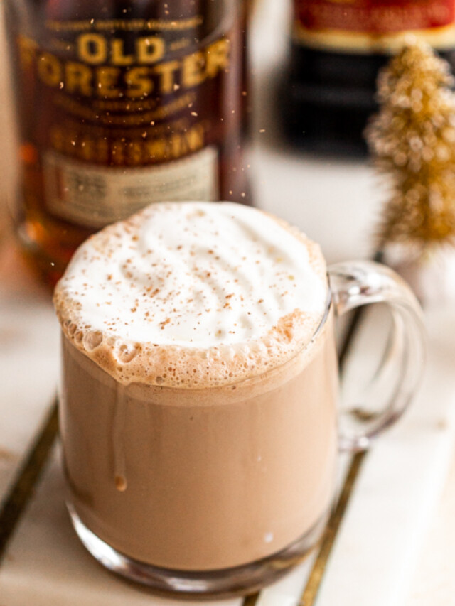 spiked hot chocolate in a glass mug with whipped cream and nutmeg