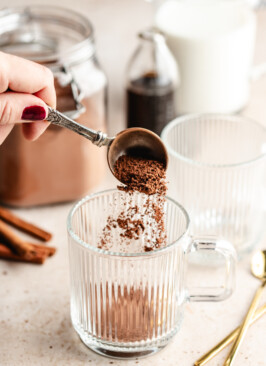 healthier hot cocoa mix being sprinkled into empty glass mug