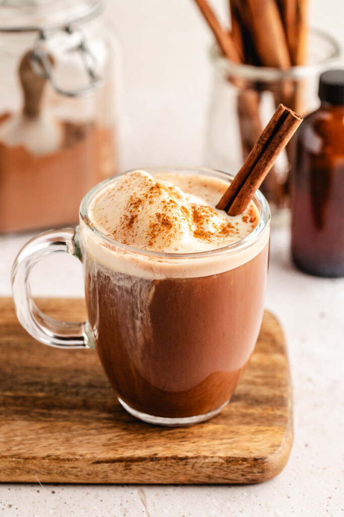Bone Broth Hot Chocolate in a glass mug topped with cool whip, cinnamon and a cinnamon stick