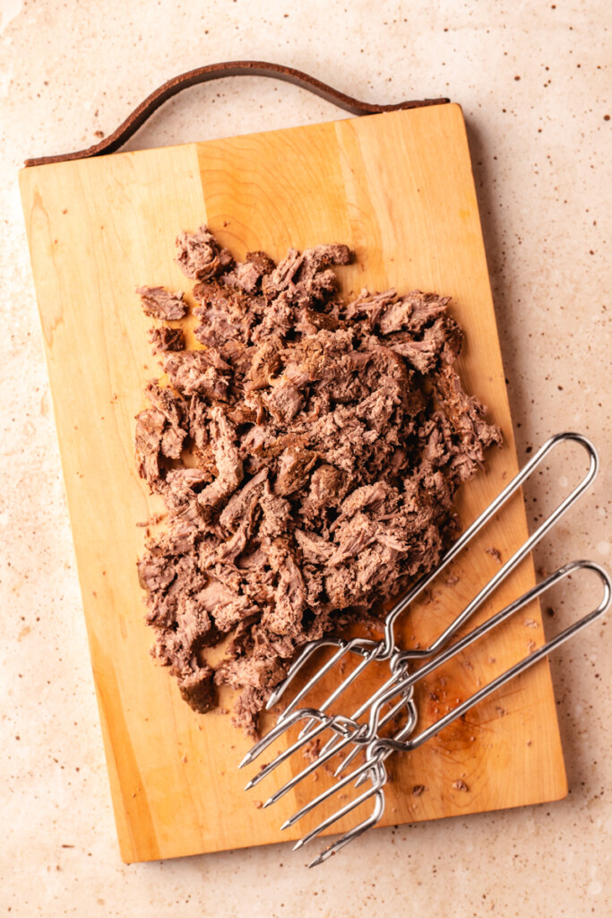 Venison roast shredded on wooden cutting board