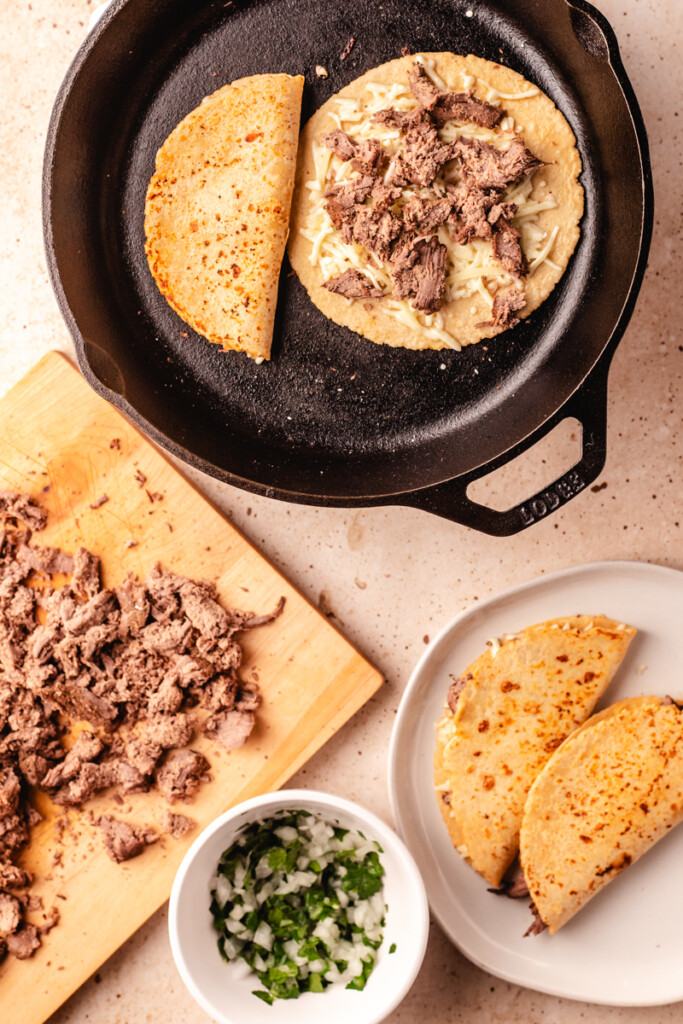 Venison Birria Tacos cooking in cast iron pan