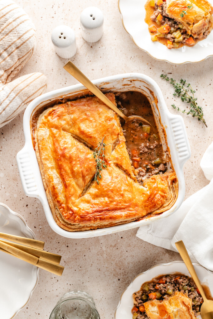 Venison Pot Pie being served on white plates with gold utensils