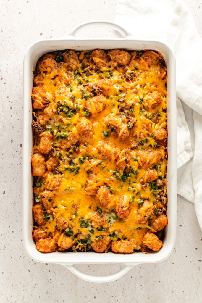 Venison Breakfast Casserole in a white dish with melted shredded cheddar cheese on top