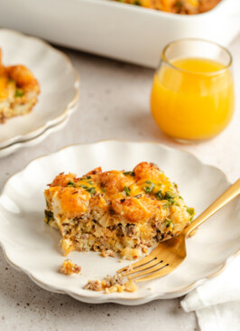 A breakfast casserole on a white plate served with juice