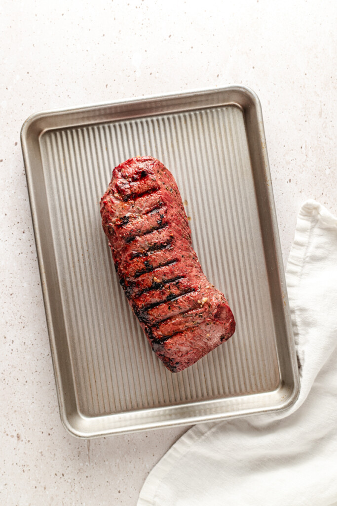 A grilled venison backstrap resting on a silver tray