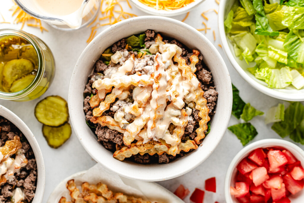A venison burger bowl in a white bowl with fresh ingredients surrounding it
