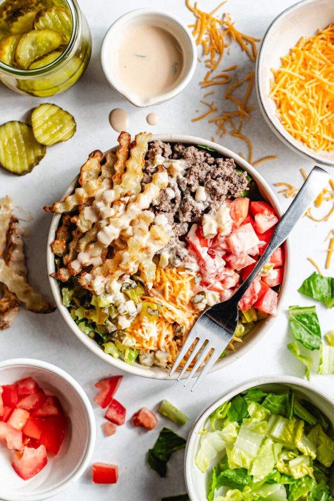 A venison burger bowl with a fork on top of the bowl with fresh ingredients surrounding it